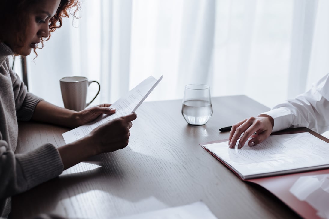 Young Woman Reading Adoption Documents in Front of Social Worker